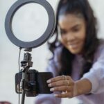 a woman setting up a smartphone and ring light to film