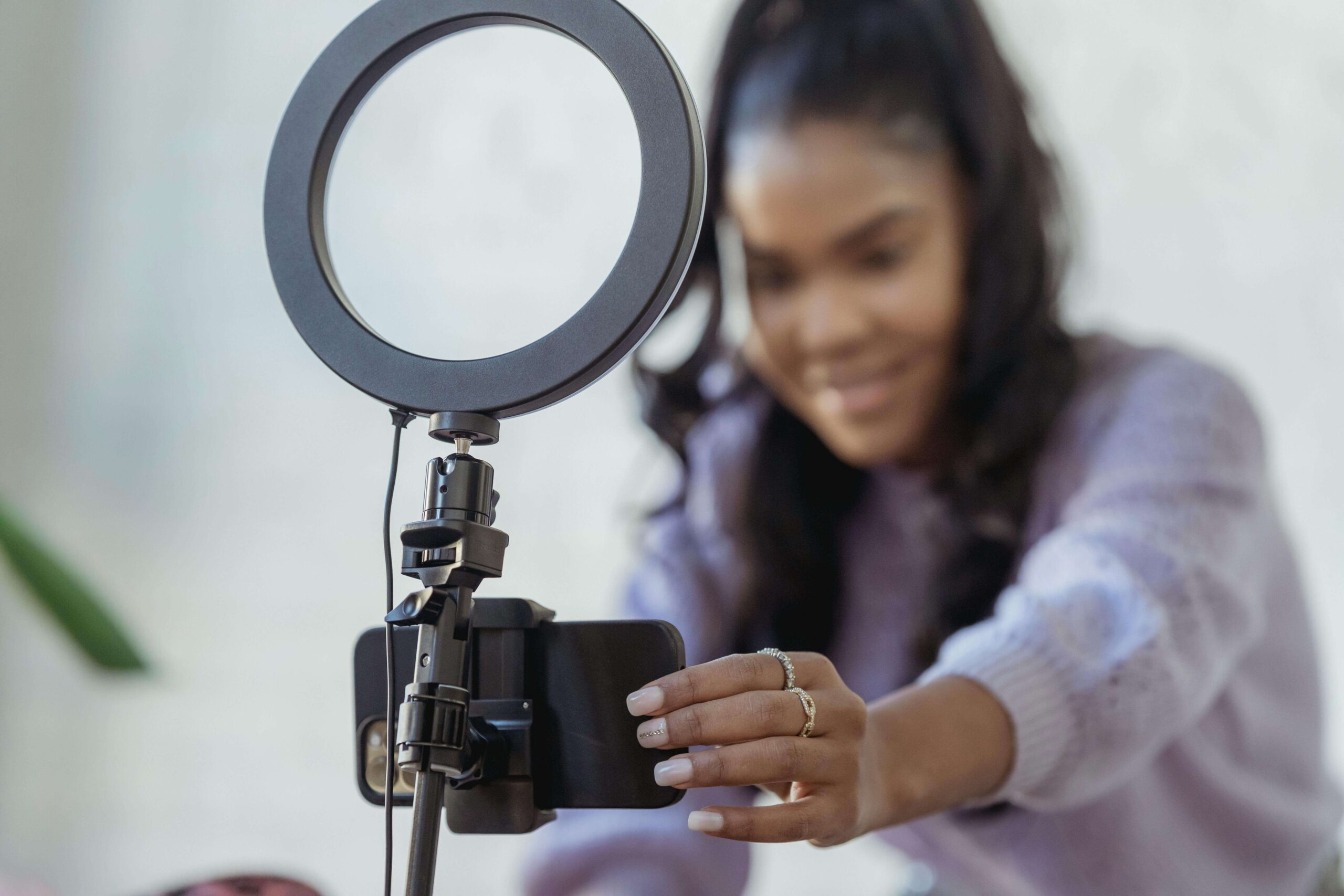 a woman setting up a smartphone and ring light to film