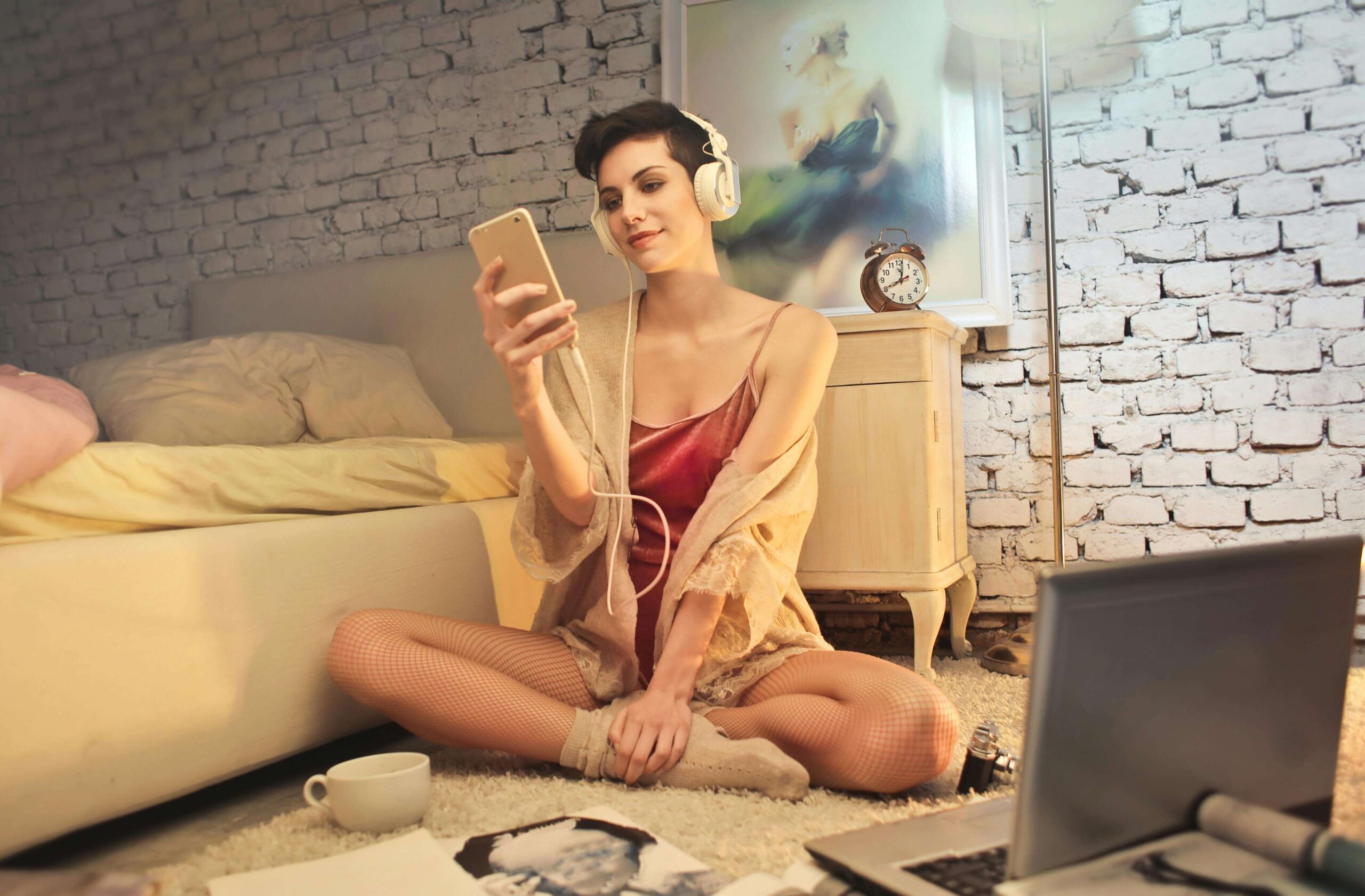 a woman in lingerie in front of a laptop web camera messaging on her smartphone